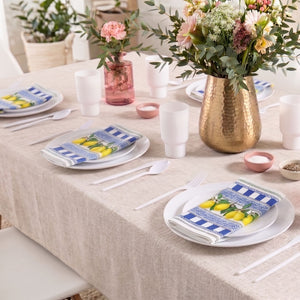 Elegant Shavuos table setting with white disposable plates and floral centerpiece