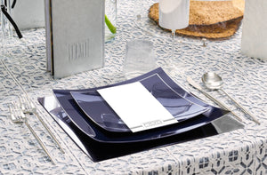 Seder Table setting with blue plates, silver cutlery, and a patterned tablecloth.