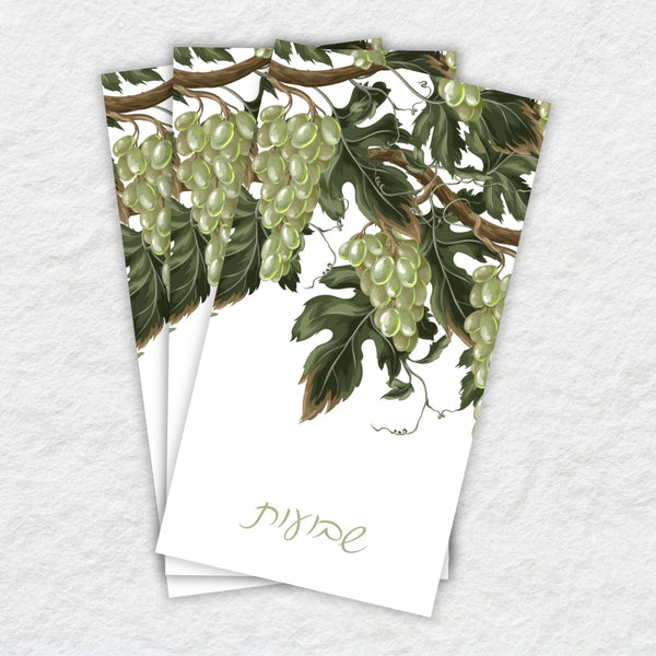 Two white napkins with green grapevine design on a textured white background