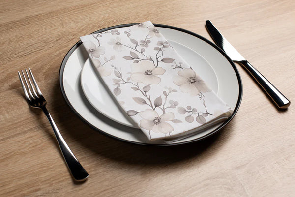 Dinner setting with floral napkin, plate, fork, and knife on a wooden table.