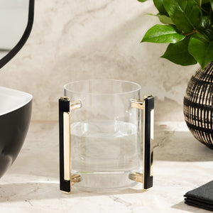 clear acrylic wash cup with black and gold handle near a powder room sink