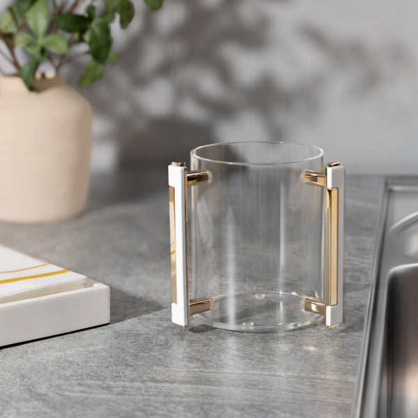 clear acrylic wash cup with white and gold handle near a powder room sink