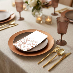 Elegant dinner table setting with gold cutlery, brown plates, and candles.