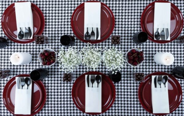 multiple place setting of red plates with black and white tablescape