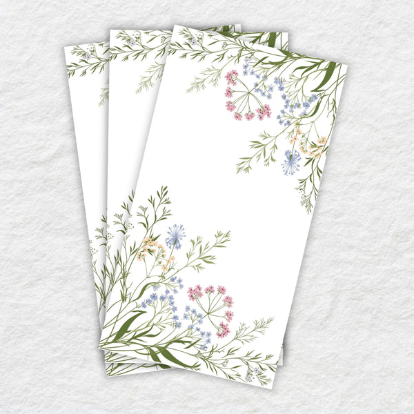 white paper napkins with floral and leaf designs on a textured gray background