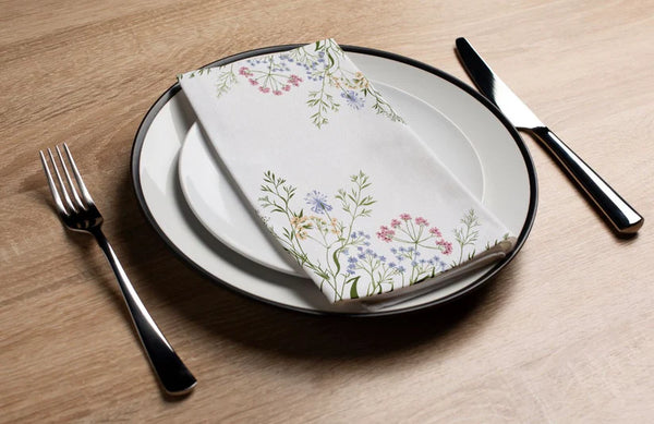 Set table with floral napkin, plates, knife, and fork on a wooden surface