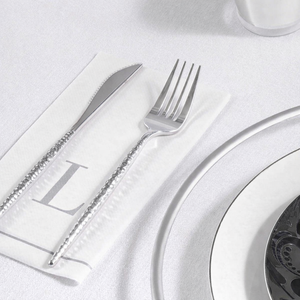 Silver knife and fork on a white plate with a white napkin.