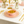Pink bowl with soup on a matching plate on a white tablecloth with gold cutlery and decor.