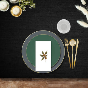 Elegant disposable dinnerware place setting with green and slate gray plates, gold plastic cutlery, ribbed clear goblet, and acorn design guest napkin on a black tablecloth.