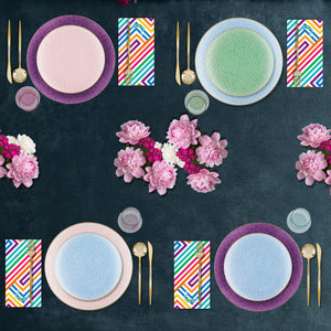 Colorful table setting with plates, napkins, and flowers on a dark surface