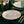 Elegant table setting with white plates, gold cutlery, and green glasses on a dark surface.