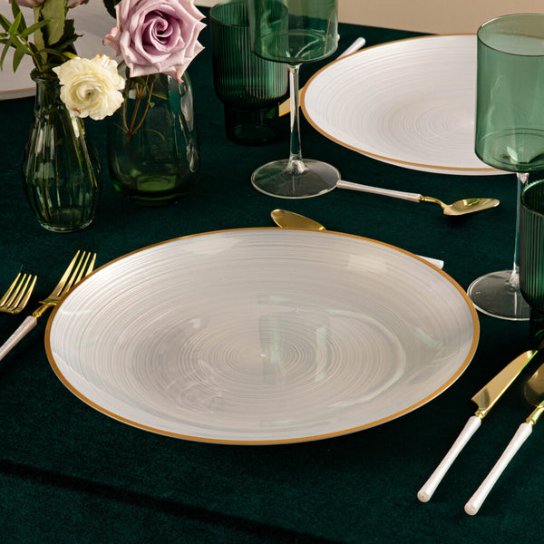 Elegant table setting with white plates, gold cutlery, and green glasses on a dark surface.