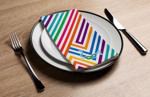 Colorful striped napkin on a white plate with silverware on a wooden table