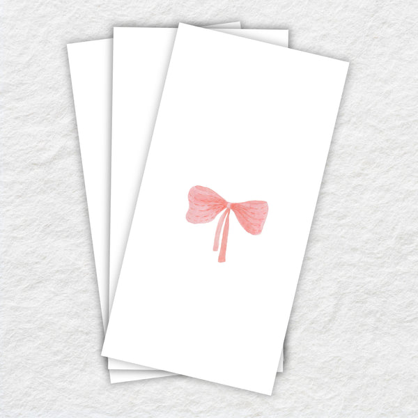 White paper napkin with a pink bow design on a textured white background
