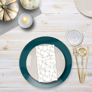 Table setting with teal plates, gold cutlery, and white pumpkins on a wooden surface.