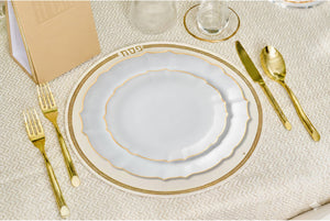 Elegant table setting with gold-rimmed plates, cutlery, and glasses on a textured surface.